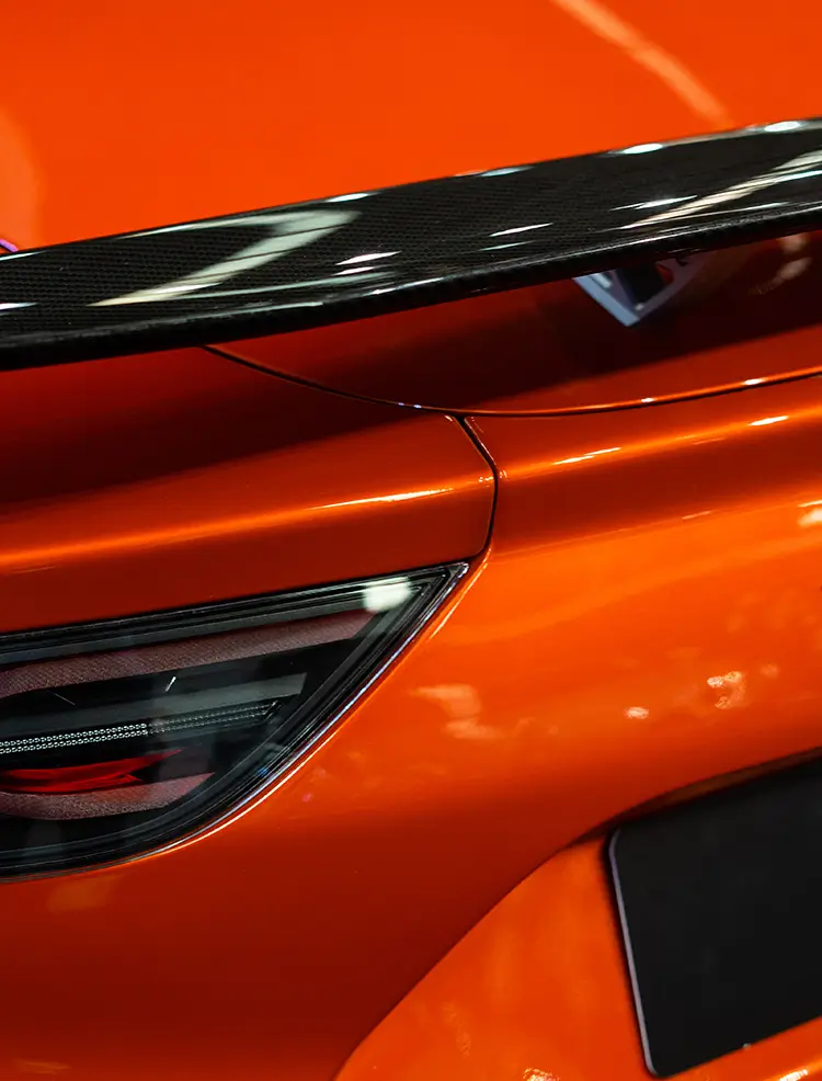 Close-up of orange wrapped vehicle with gloss black rear spoiler