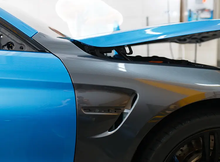 Blue vinyl wrap being applied to a vehicle front fender