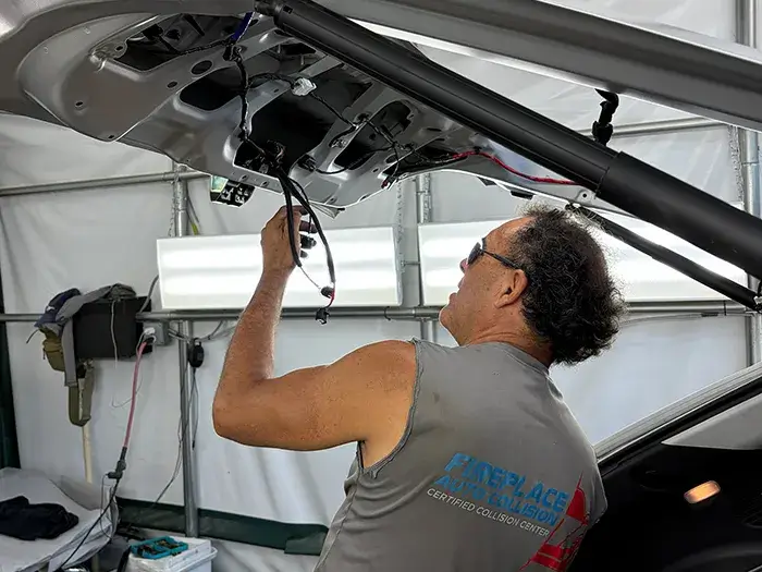 Collision repair technician reinstalling liftgate components at Fireplace Auto Collision in East Hampton, NY.