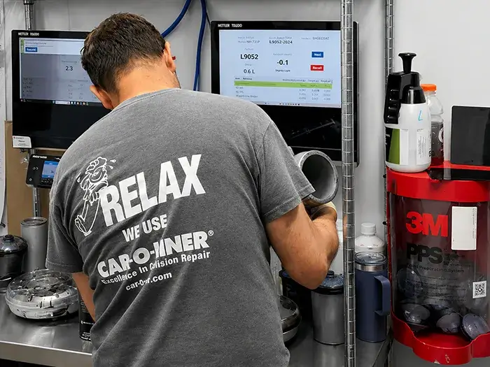 Technician sanding a vehicle panel during the refinishing process at Fireplace Auto Collision in East Hampton, NY.