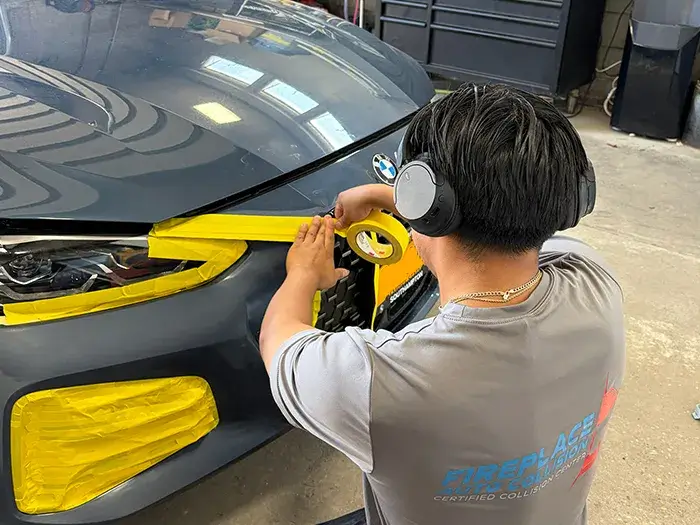 Technician masking a BMW before automotive paint refinishing at Fireplace Auto Collision.