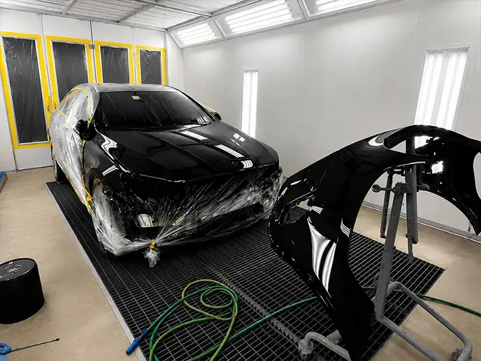 Vehicle undergoing automotive paint refinishing inside the paint booth at Fireplace Auto Collision.