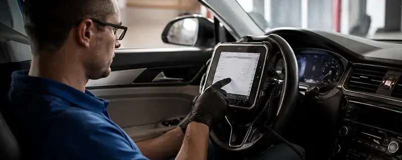 Technician performing vehicle diagnostics and ADAS calibration using advanced scan tools